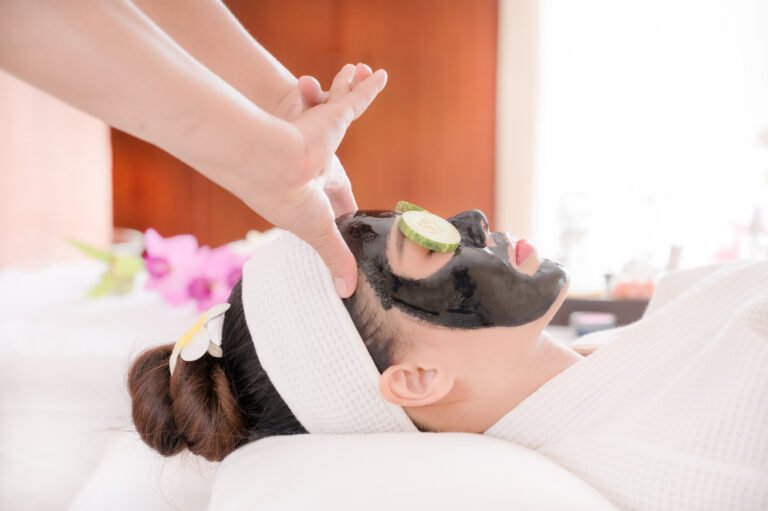 A beautiful Asian woman uses spa mud and cucumber for facial treatment, along with a massage by a professional masseuse in the spa salon
